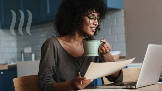 Woman drinking mushroom coffee from a cup in the morning while working in her laptop
